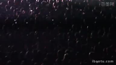 在一场摇滚音乐会上，聚光灯照亮了<strong>欢呼</strong>的歌迷